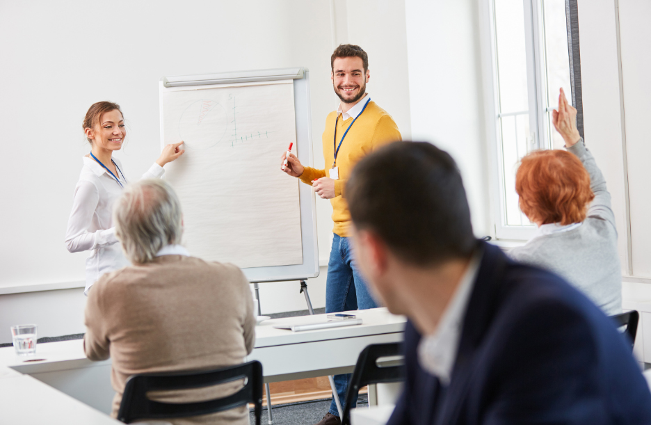 Man in mustard jumper taking questions from people in workshop