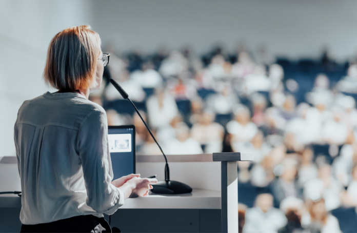 Woman speaking in front of crowd at conference