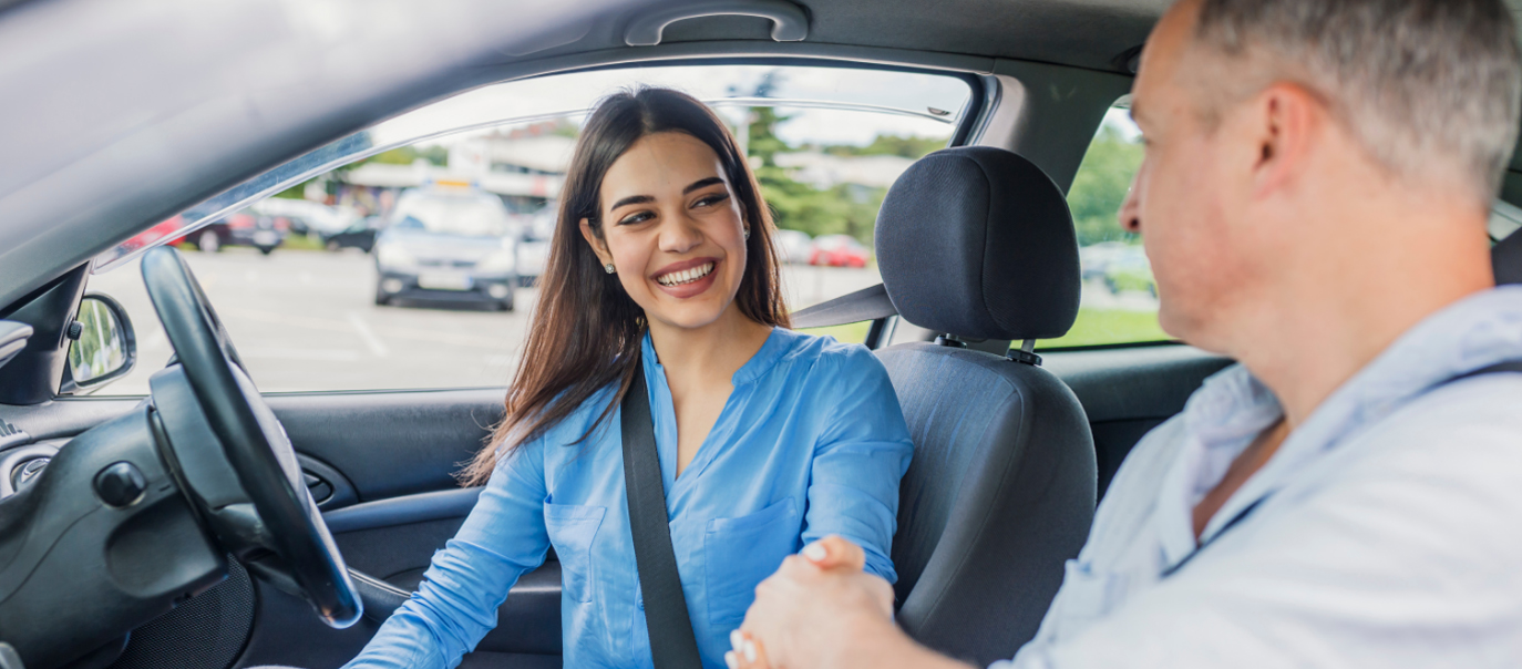 Female smiling and shaking hands with male driving instructor